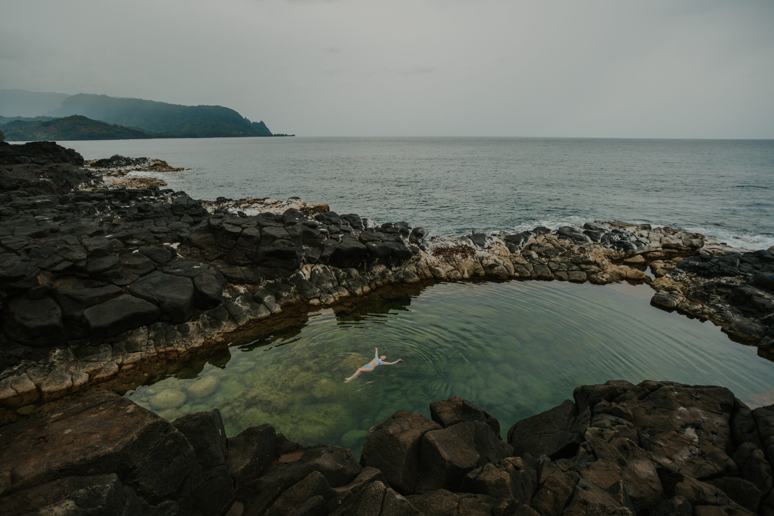 woman in bikini relaxes in a pool of water in kauai, hawaii